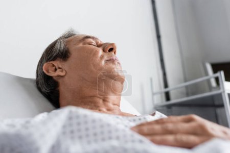 Photo for Low angle view of sick elderly man lying on bed in hospital ward - Royalty Free Image