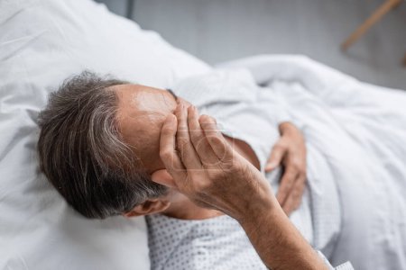 Téléchargez les photos : Overhead view of sick elderly man lying on bed in hospital ward - en image libre de droit