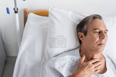 Blick aus der Vogelperspektive: Seniorin im Mantel liegt auf Krankenhausstation im Bett