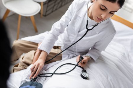 Téléchargez les photos : High angle view of doctor checking blood pressure of elderly patient on bed in hospital - en image libre de droit