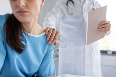 Téléchargez les photos : Cropped view of senior doctor with paper folder calming patient in hospital ward - en image libre de droit