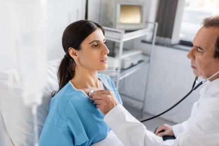 Oberarzt untersucht Lungen von Patient auf Krankenhausstation 