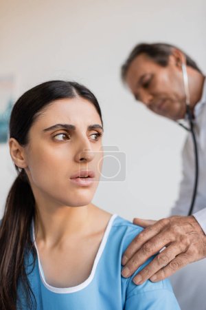 patient breathing near blurred doctor with stethoscope in hospital ward 