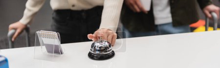 cropped view of woman ringing service bell near card holder on hotel reception, banner