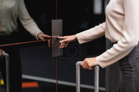 Photo pour Partial view of woman standing near reflective doors of elevator and pressing call button - image libre de droit