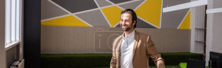 Photo for Young corporate manager in beige blazer smiling and looking away in office, banner - Royalty Free Image