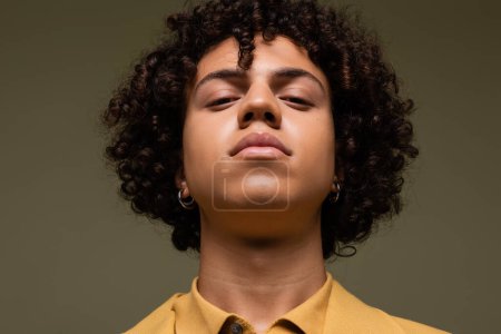 retrato de un joven afroamericano con el pelo rizado mirando a la cámara aislada en gris