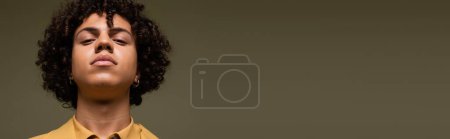 retrato de hombre afroamericano joven y elegante mirando la cámara aislada en gris, pancarta