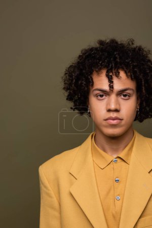 vista frontal del joven afroamericano en blazer amarillo y camisa mirando a la cámara aislada en gris