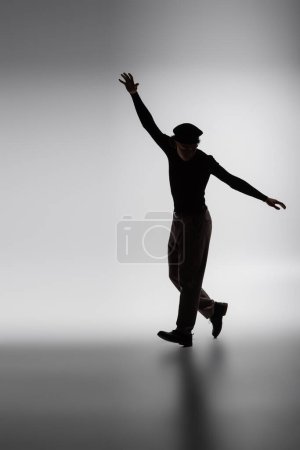 black silhouette of african american man walking with outstretched hands on grey background