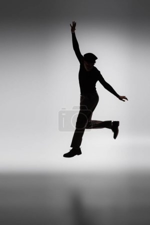 Photo for Dark silhouette of young african american man jumping on grey background - Royalty Free Image