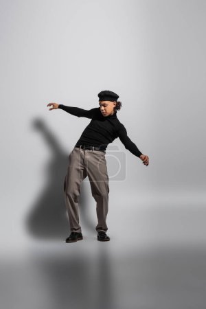 Photo for Full length of young and stylish african american guy in black beret and turtleneck with pants posing on grey background - Royalty Free Image