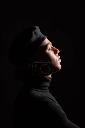 Téléchargez les photos : Side view of fashionable african american man in turtleneck and sweater isolated on black - en image libre de droit