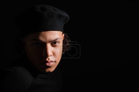 portrait of african american man in dark beret looking at camera isolated on black