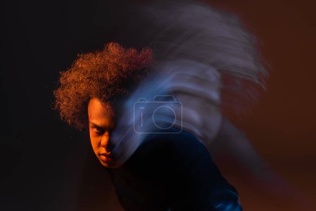 double exposure of wounded and angry african american man with broken nose on dark background with red and blue light