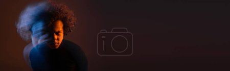 Foto de Larga exposición del hombre afroamericano lesionado con trastorno bipolar y cara sangrante sobre fondo negro con luz naranja y azul, pancarta - Imagen libre de derechos