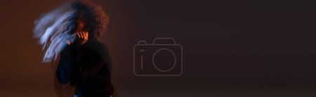 Téléchargez les photos : Flou de mouvement de l'homme afro-américain bouclé avec trouble bipolaire sur fond sombre avec lumière bleue et orange, bannière - en image libre de droit
