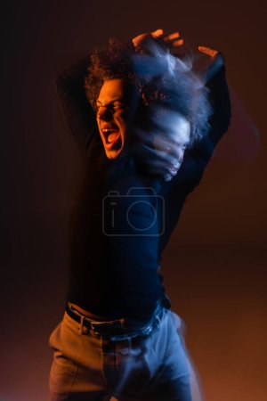 Foto de Doble exposición del hombre afroamericano herido y enojado con trastorno bipolar gritando sobre fondo oscuro con luz naranja y azul - Imagen libre de derechos