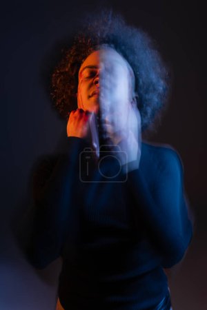 double exposure of wounded african american man with bloody face standing with closed eyes on black with red and blue light