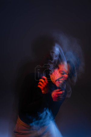 double exposure of stressed african american man with injured bleeding face grimacing on dark with red and blue light