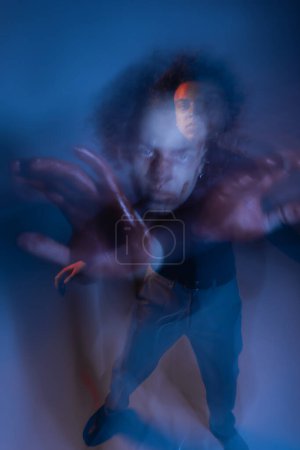 Téléchargez les photos : Double exposition de l'homme afro-américain blessé avec trouble dissociatif de l'identité gestuelle sur sombre avec lumière bleue - en image libre de droit
