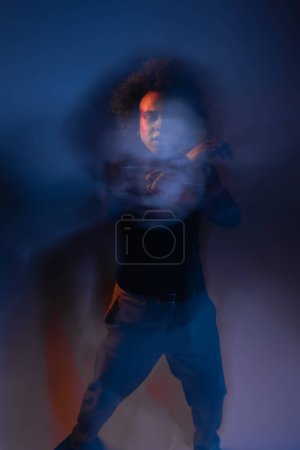 Foto de Doble exposición del hombre afroamericano abusado con cara lesionada y trastorno bipolar en la oscuridad con luz naranja y azul - Imagen libre de derechos