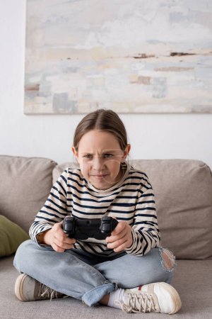 Foto de KYIV, UKRAINE - NOVEMBER 28, 2022: tensed girl holding joystick while playing video game - Imagen libre de derechos