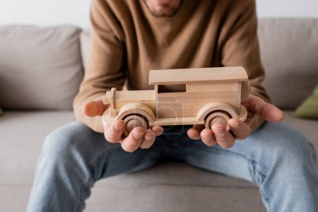 Photo for Cropped view of bearded man holding wooden car toy in living room - Royalty Free Image