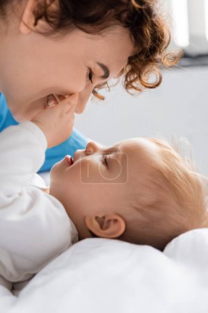 Téléchargez les photos : Side view of smiling toddler girl touching face of happy mother in hospital ward - en image libre de droit