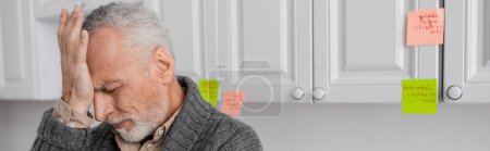 Téléchargez les photos : Stressed man with alzheimer disease touching forehead in kitchen, banner - en image libre de droit
