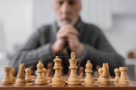 selective focus of chessboard near senior man with alzheimer syndrome on blurred background