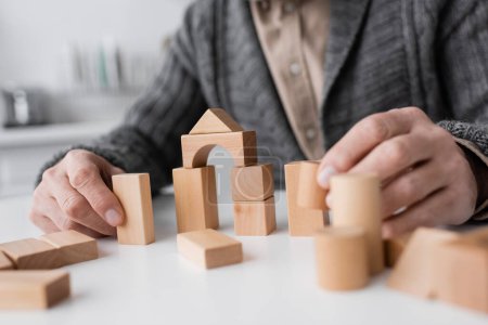 cropped view of senior man suffering from alzheimer syndrome and playing with wooden blocks at home