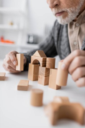 Photo for Partial view of man with alzheimer disease playing building blocks game on blurred foreground - Royalty Free Image