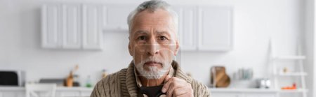 Photo for Aged and depressed man with alzheimer syndrome looking at camera at home, banner - Royalty Free Image