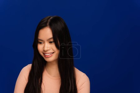Photo for Smiling asian woman looking away isolated on blue - Royalty Free Image