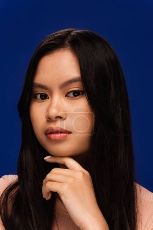 Photo for Portrait of young asian woman looking at camera isolated on blue - Royalty Free Image
