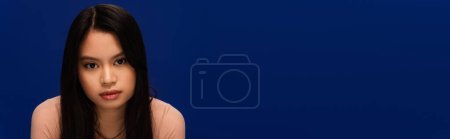 Foto de Young asian woman looking at camera isolated on blue with copy space, banner - Imagen libre de derechos