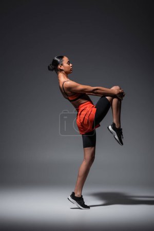 Photo pour Full length of sportive african american woman in sneakers training on grey - image libre de droit