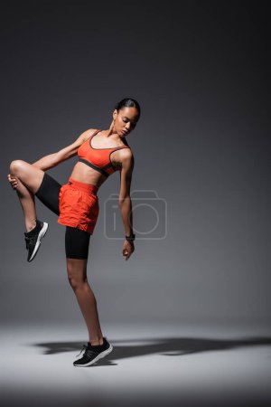 Foto de Full length of sportive and young african american woman in sneakers exercising on grey - Imagen libre de derechos