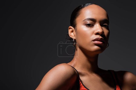 Photo for Portrait of sportive african american woman in sports bra looking at camera isolated on grey - Royalty Free Image