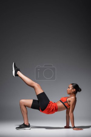 Téléchargez les photos : Side view of strong african american woman working out on grey background - en image libre de droit