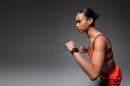 Photo for Brunette african american woman in sports bra and shorts gesturing on grey background - Royalty Free Image