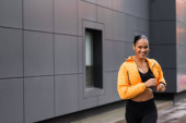 positive african american sportswoman in yellow puffer jacket jogging outside  Stickers #635597428