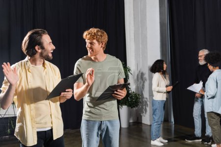 Foto de Happy young actors with clipboards gesturing during rehearsal in acting skills school - Imagen libre de derechos