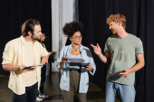 redhead man pointing with finger while talking to interracial students with screenplays in theater Stickers #637021484