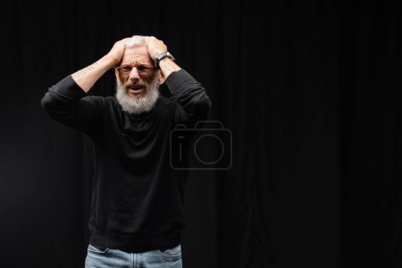 Photo for Tattooed actor with depressed face expression touching head while performing in theater. Translation of tattoo: om, shanti, peace - Royalty Free Image