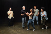 multiracial woman gesturing while rehearsing near bearded art director and smiling interracial actors Stickers #637023166