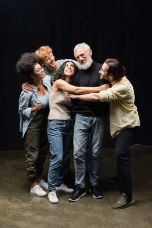 Foto de Happy multicultural students hugging acting skills teacher in theater school - Imagen libre de derechos