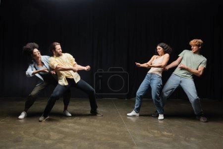 Foto de Full length on multiethnic students imitating pull rope game while rehearsing in theater - Imagen libre de derechos