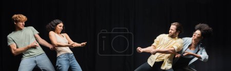 Foto de Young interracial actors imitating pull rope game in theater, banner - Imagen libre de derechos